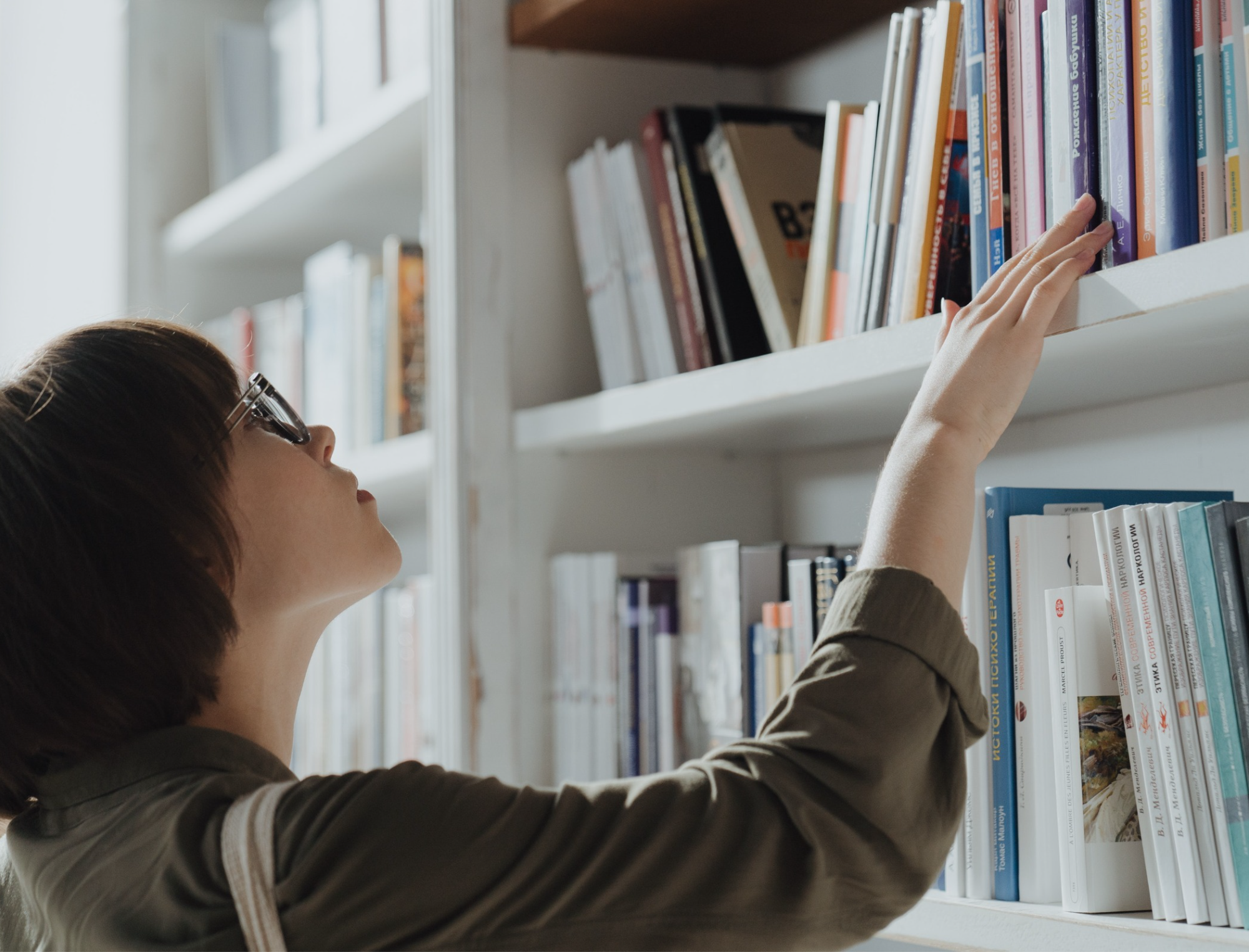 A woman looks at a bookshelf. Learn how to publish your book in 6 months with Publish Your Purpose.