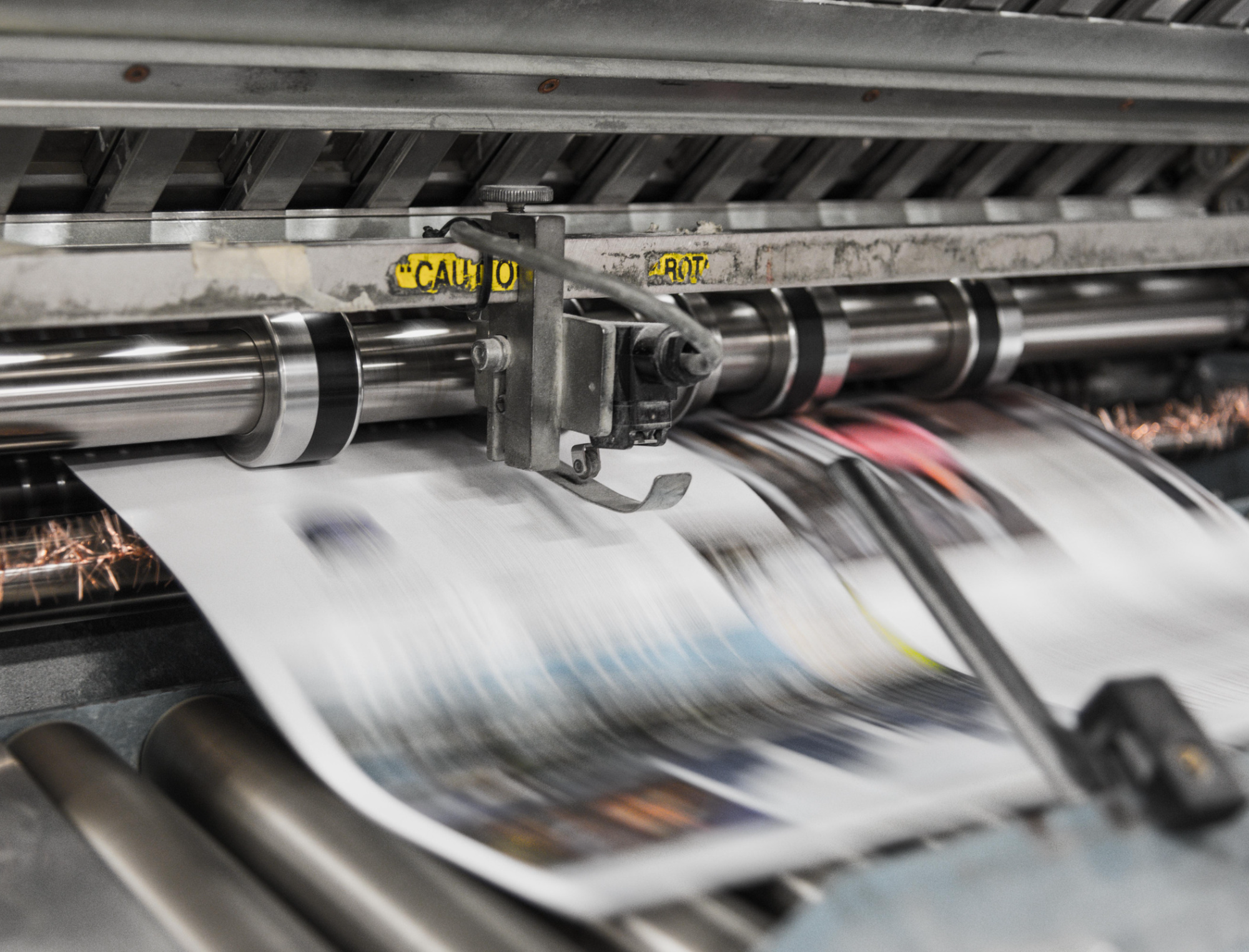 Machine prints pages below caution sign. Learn how to avoid vanity publishers with Publish Your Purpose. Photo: Bank Phrom