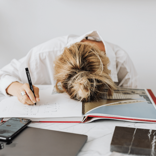 Woman with head on desk. Learn how to overcome writer procrastination with Publish Your Purpose.