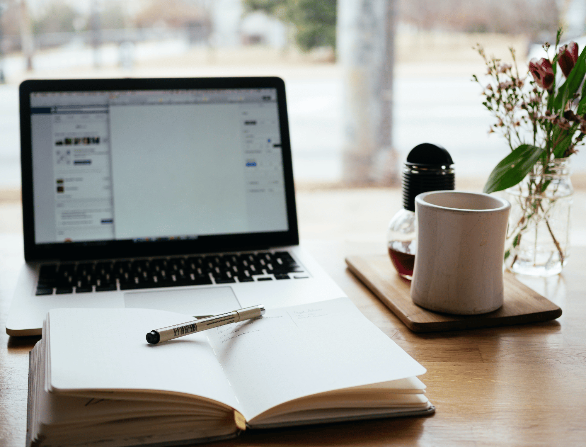 An open laptop and notebook on a table. Writing a non-fiction book is possible with the guidance of Publish Your Purpose.